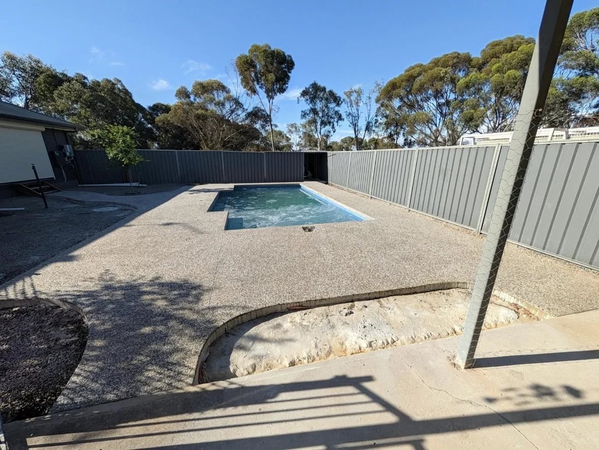 Exposed aggregate concrete around a finished pool in Two Wells